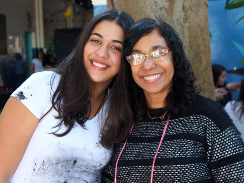 Foto da psicóloga com a filha Sofia. Elas estão lado a lado com as cabeças encostadas e sorriem para a foto